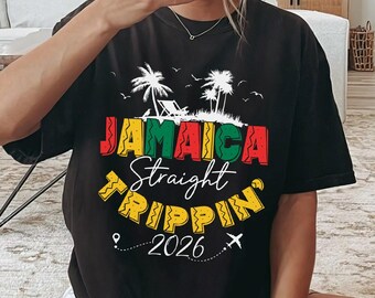 May include: Black t-shirt with the text "JAMAICA Straight Trippin' 2026" in colorful lettering. The design includes palm trees and a small airplane icon, suggesting a travel theme. The shirt is a casual wear item.