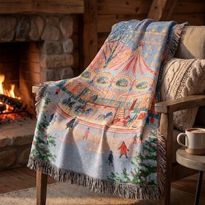 May include: A woven throw blanket featuring a colourful illustration of a carousel in a snowy setting with people walking nearby. The blanket has a fringed edge and displays a scene with a red and white striped carousel canopy, trees, and figures.