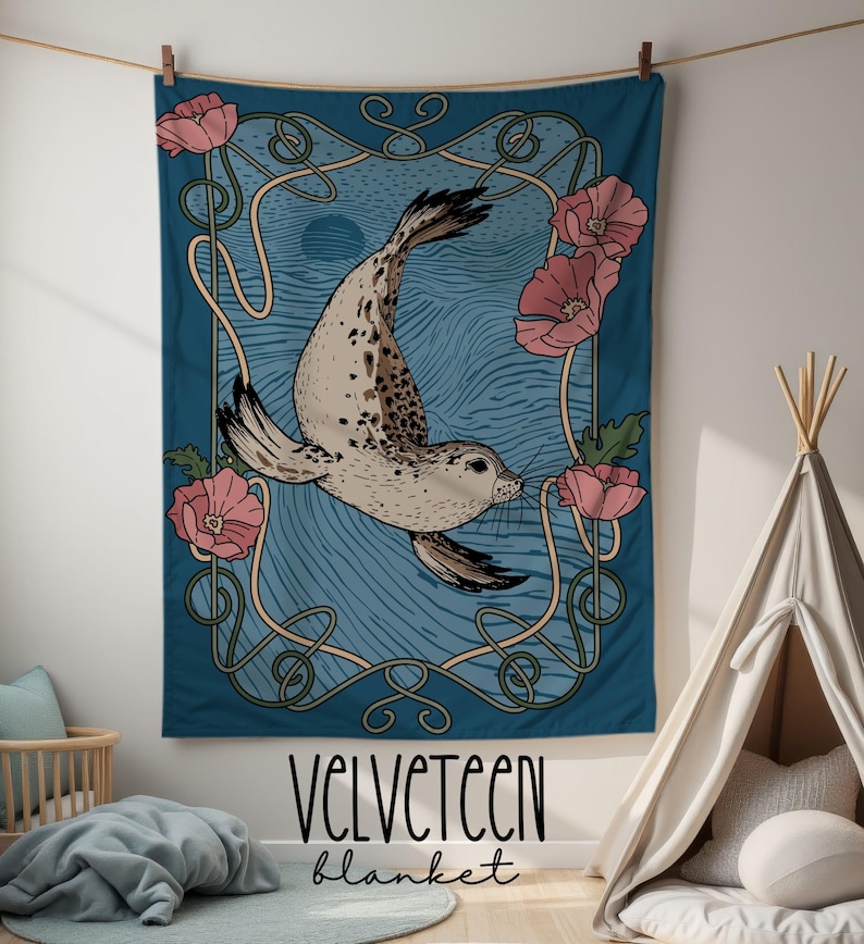 Peut inclure: Une couverture Velveteen turquoise avec une illustration de phoque, des fleurs roses et un cadre de style Art nouveau. La couverture porte les mots "Velveteen" et "blanket".