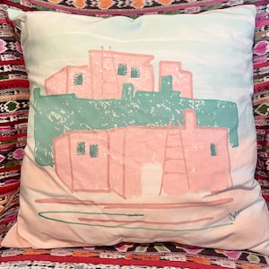 May include: A pink and green pillow with a stylized illustration of a building. The pillow has a light beige background and the text "Chasen" is in the bottom right corner.