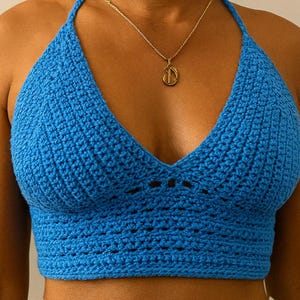 May include: A bright blue crocheted halter top with a deep V-neckline. The top is made with a fine yarn and has a delicate, intricate stitch pattern.