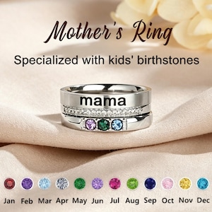 May include: A silver-toned stackable ring set featuring the word mama engraved on the top band, a middle band with clear stones, and a bottom band with three coloured birthstones. Below, a chart displays twelve birthstone colours by month.