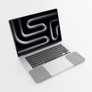 May include: A silver laptop with a black screen displaying a white and black abstract design. Two gray, rectangular trackpad covers are placed on the laptop. The keyboard is black with white keys.