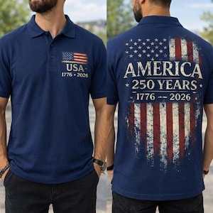 May include: Navy blue polo shirt with the American flag and the text "USA 1776-2026" on the front. The back features a distressed American flag design with the words "AMERICA 250 YEARS 1776-2026".