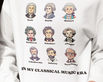 May include: White sweatshirt with a graphic print of famous composers, including Bach, Haydn, Mozart, Beethoven, Schubert, Chopin, Tchaikovsky, Debussy, and Stravinsky. The text "IN MY CLASSICAL MUSIC ERA" is printed below the images.