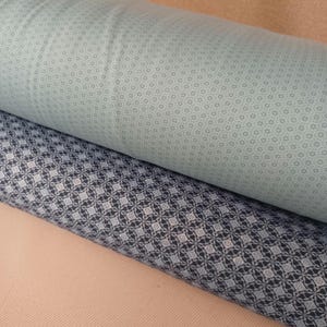 Könnte beinhalten: Zwei Stoffrollen, eine mit hellblauem Hintergrund und einem kleinen weißen Blumenmuster und die andere mit dunkelblauem Hintergrund und einem weißen geometrischen Muster.