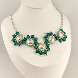 May include: A green and silver beaded necklace with a central cluster of three large, iridescent crystals surrounded by smaller green beads.