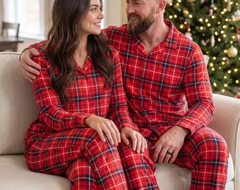 May include: Matching two-piece pajama sets featuring a vibrant red, black, and white plaid pattern. Each set consists of a long-sleeved button-down shirt with a notched collar and coordinating full-length trousers with a relaxed, comfortable fit.