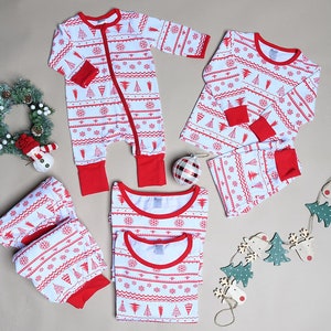 May include: A collection of white pajamas featuring a red pattern of Christmas trees, snowflakes, and wavy lines. The set includes a long-sleeve romper with a zipper, two-piece pajama sets with long sleeves and pants, all with red cuffs and necklines.
