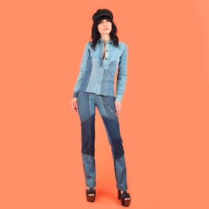 May include: A denim patchwork shirt and matching pants set. The shirt has a button-up front and long sleeves. The pants are straight-legged with a patchwork design. The outfit is in shades of blue denim and is worn with a black cap and platform shoes.