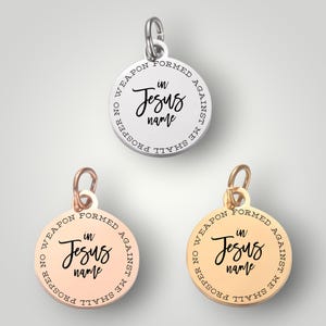 May include: Three round silver, gold, and rose gold charms with the inscription "No weapon formed against me shall prosper, in Jesus name".