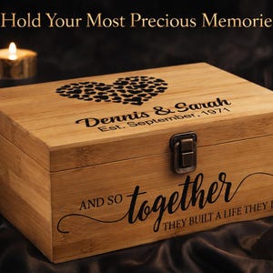 May include: A wooden memory box with a heart design on the lid. The box is engraved with the names "Dennis & Sarah" and the date "Est. September, 1971". The words "AND SO together THEY BUILT A LIFE THEY LOVED" are also engraved on the box.