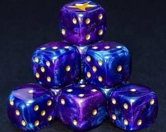 May include: Six dice stacked in a pyramid formation. The dice are a mix of blue and purple with gold-colored dots and a gold star on the top die. The dice are for a board game.