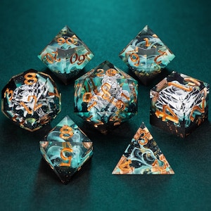 Könnte beinhalten: Ein Satz von sieben polyedrischen Würfeln in Teal und Gold. Die Würfel sind transparent und weisen wirbelnde Muster und goldene Zahlen auf. Sie liegen auf einer dunkelgrünen Oberfläche.