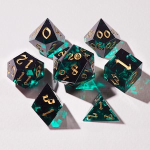 May include: A collection of seven multi-sided dice, including a d4, d6, d8, d10, d12, d20, and a percentile die. The dice are black with gold numerals and a green, swirling interior. The dice are displayed on a white surface.