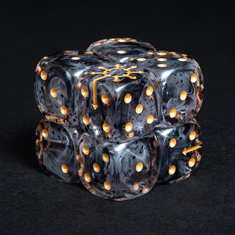 May include: Six black and gray marbled dice with gold-colored pips and symbols are stacked together. The dice have a swirling pattern and are arranged in a cube shape. The dice are for a tabletop game.