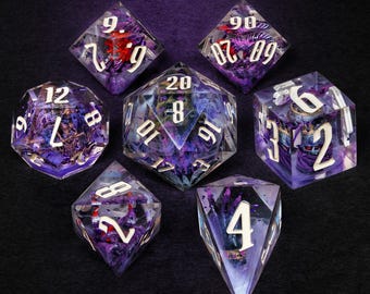 Puede incluir: Juego de siete dados poliédricos con un diseño de resina morada y transparente. Los dados tienen numeración blanca y detalles internos. Perfectos para juegos de rol de mesa.