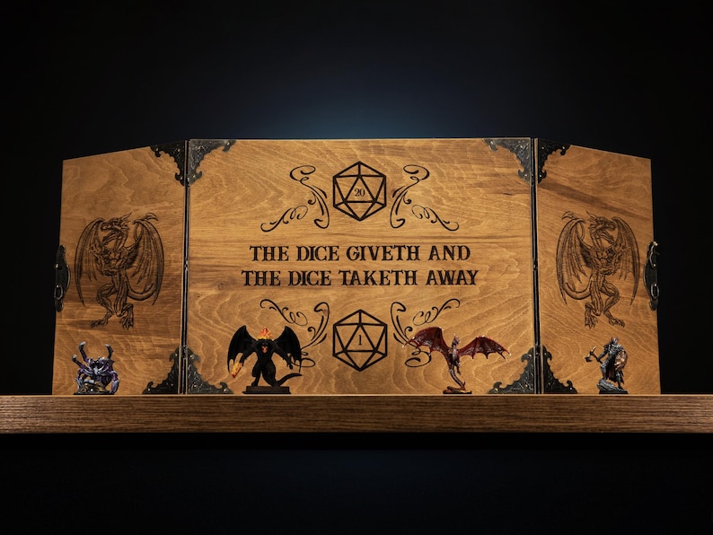 Może przedstawiać: Drewniany ekran do gier stołowych z grawerowanymi wzorami kości i smok&oacute;w. Centralny panel głosi "THE DICE GIVETH AND THE DICE TAKETH AWAY". Zawiera miniaturowe figurki na drewnianej p&oacute;łce.