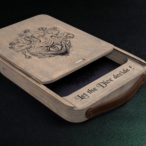 May include: Wooden dice box with a hinged lid, featuring a detailed engraved monster design. The box has a leather handle and the text "Let the Dice decide!" is printed on the side. The box is open, revealing a dark interior.