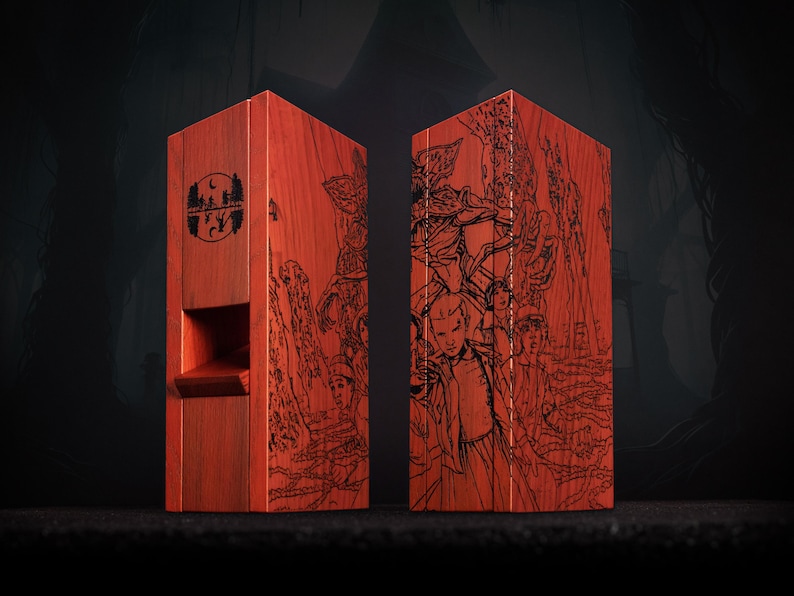 May include: Two red wooden boxes with black etched illustrations. One box features a logo with a moon and trees, the other depicts characters. The boxes are rectangular with a slot on one side.