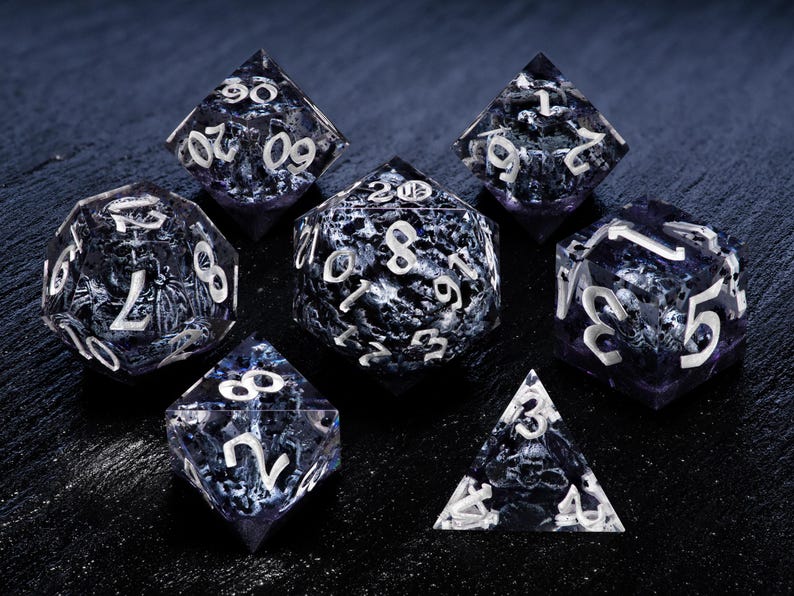 K&ouml;nnte beinhalten: Set aus sieben polyedrischen W&uuml;rfeln mit einem dunkelblauen und wei&szlig;en Marmormuster. Jeder W&uuml;rfel hat wei&szlig;e Zahlen. Die W&uuml;rfel sind f&uuml;r Tabletop-Rollenspiele konzipiert und werden auf einer dunklen Oberfl&auml;che pr&auml;sentiert.