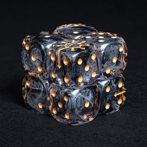 May include: Six black and gray marbled dice with gold-colored pips and symbols are stacked together. The dice have a swirling pattern and are arranged in a cube shape. The dice are for a tabletop game.