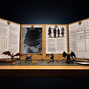 Może przedstawiać: Konfiguracja gry fabularnej na stole z drewnianym ekranem DM z wydrukowanymi stronami i mapą. Miniaturowe figurki fantastycznych stworzeń i postaci są ułożone na zielonej powierzchni, wraz z kośćmi i długopisem.