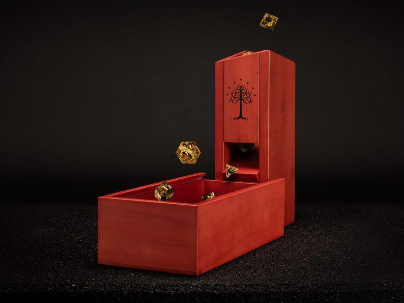 May include: A red wooden dice tower and tray set with a tree design. Several gold-coloured dice are shown in the air and inside the tray. The tower has a slot for the dice to roll through.