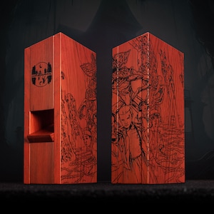 May include: Two red wooden boxes with black etched illustrations. One box features a logo with a moon and trees, the other depicts characters. The boxes are rectangular with a slot on one side.