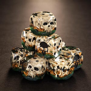 May include: A stack of seven dice with a skull design. The dice are clear with a skull and bone design inside. The dice have a green and gold base. The dice are stacked on a dark surface.