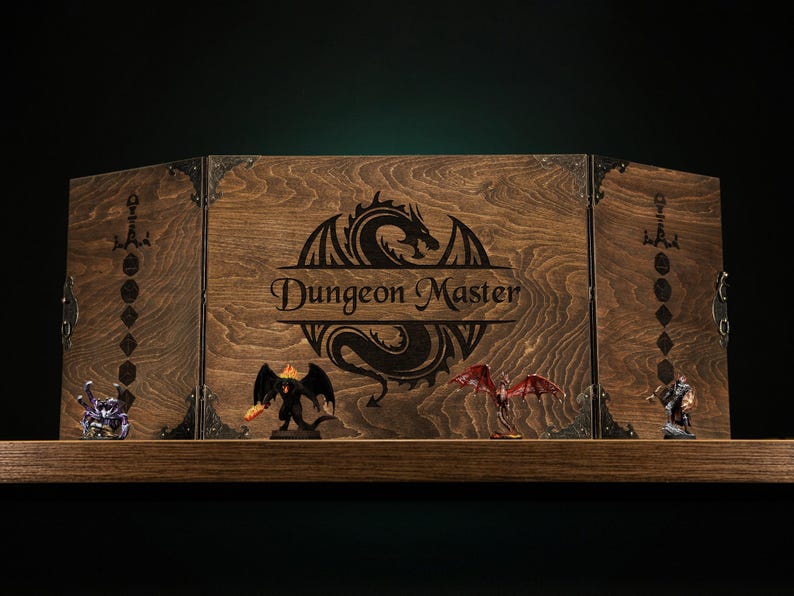 Może przedstawiać: Drewniany ekran Dungeon Master z motywem smoka i napisem "Dungeon Master". Ekran jest brązowy z metalowymi narożnikami. Miniaturowe figurki fantasy są wyświetlane na p&oacute;łce przed ekranem.