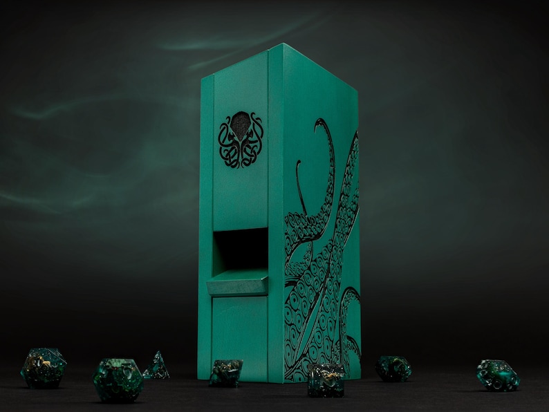 May include: A teal dice tower featuring a black tentacle design and a decorative emblem. Several green and gold dice are scattered around the base of the tower, creating a thematic tabletop gaming scene.