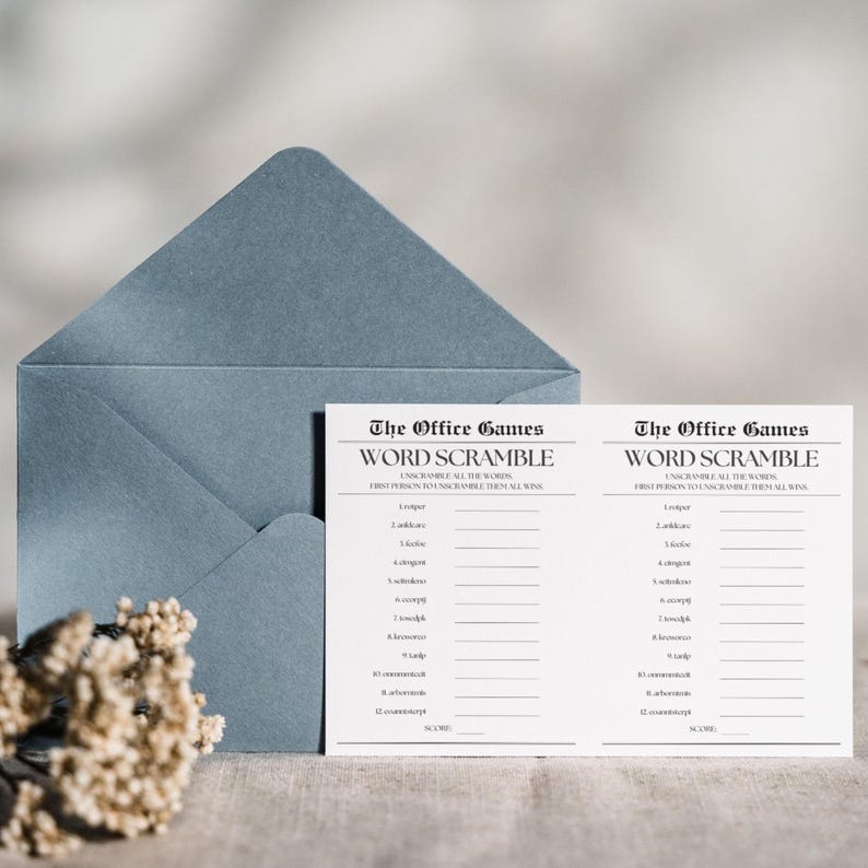 Op de afbeelding: Twee witte kaarten met zwarte tekst die "The Office Games Word Scramble" zegt en instructies om de woorden te ontcijferen. De kaarten liggen op een lichtblauwe envelop met een wit bloemenboeket.
