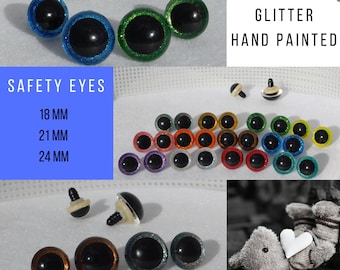 May include: Assortment of glitter safety eyes for crafts. The eyes are hand-painted with various colors, including green, blue, red, orange, purple, and silver. The eyes are available in three sizes: 18 mm, 21 mm, and 24 mm.  "GLITTER HAND PAINTED" and "GLASSEYESONLINE" are written in the image.