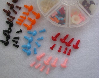 May include: Assortment of plastic safety eyes and noses in various colors, including black, brown, orange, blue, pink, and red. The eyes and noses are packaged in a clear plastic container with multiple compartments. The container is labeled "TN-48 Assortment Triangle Nose (Button / Eyes)" and "GlassEyesOnline".