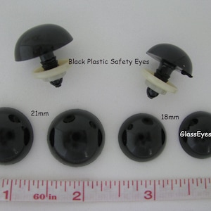 May include: Black plastic safety eyes for crafts. The eyes are 18mm and 21mm in diameter. The eyes have a white washer and a black screw post.