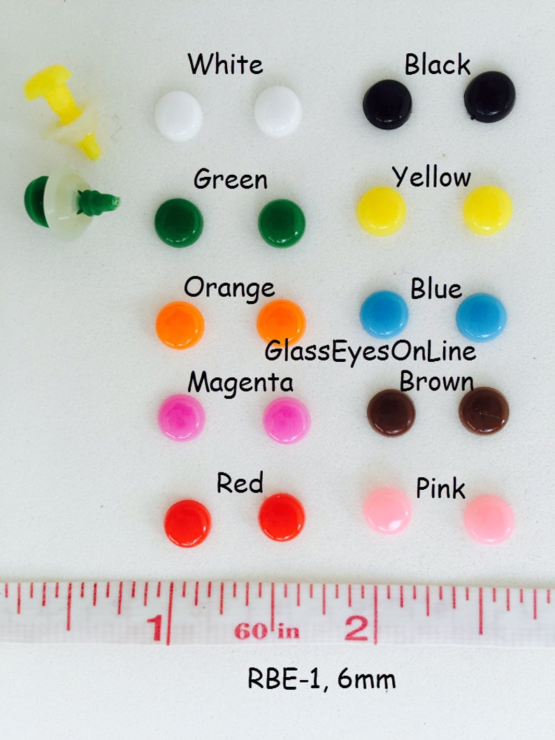 K&ouml;nnte beinhalten: Sortiment von 6 mm gro&szlig;en Kunststoffaugen in verschiedenen Farben, darunter Wei&szlig;, Schwarz, Gr&uuml;n, Gelb, Orange, Blau, Magenta, Braun, Rot und Pink. Die Augen sind nach Farben in Reihen angeordnet. Ein Lineal ist als Gr&ouml;&szlig;enreferenz enthalten. Das Lineal zeigt "60 in" und "RBE-1, 6mm".