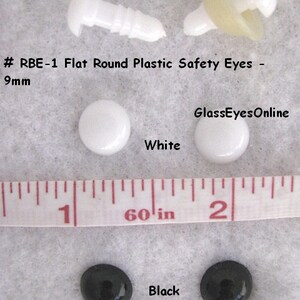 K&ouml;nnte beinhalten: Nahaufnahme eines Sets flacher runder Sicherheitsaugen aus Kunststoff in Wei&szlig; und Schwarz. Die Augen sind neben einem Lineal mit der Aufschrift "60 in" abgebildet. Der Text "#RBE-1 Flat Round Plastic Safety Eyes - 9mm" und "GlassEyesOnline" ist ebenfalls auf dem Bild zu sehen.