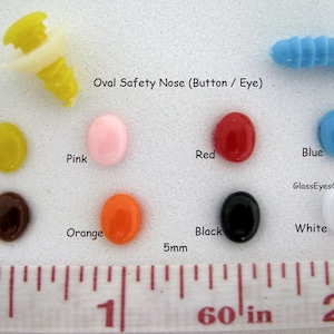 May include: Assortment of oval-shaped safety eyes and noses in various colors, including yellow, pink, red, blue, brown, orange, black, and white. The eyes and noses are 5mm in diameter and are shown next to a ruler for size reference. Oval Safety Nose (Button / Eye) GlassEyesOnLine