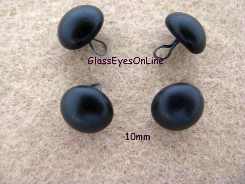 May include: Four black plastic buttons with a metal loop on the back. Each button is 10mm in diameter. GlassEyesOnline.