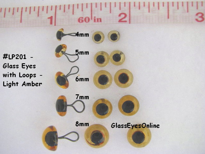 May include: Assortment of light amber glass eyes with black pupils and metal loops. The eyes are arranged in rows by size, from 4mm to 8mm. The text "#LP201 - Glass Eyes with Loops - Light Amber" and "GlassEyesOnline" are visible in the image.