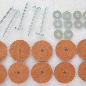 May include: A set of 12 brown felt pads, 6 silver metal washers, and 6 silver metal pins with a T-shaped head. The pins are used to attach the felt pads to the washers.