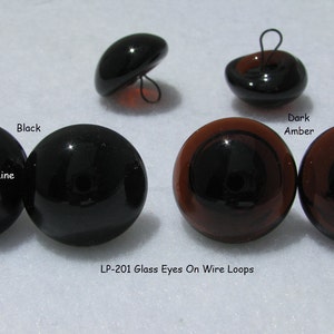 May include: Four glass eyes with wire loops. Two black eyes and two dark amber eyes. The eyes are for crafts and are sold by GlassEyesOnLine. LP-201 Glass Eyes On Wire Loops.