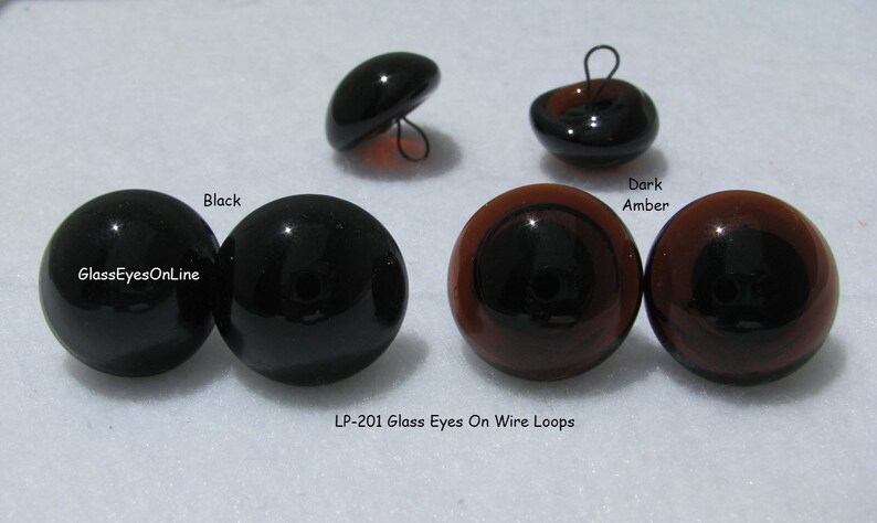 May include: Four glass eyes with wire loops. Two black eyes and two dark amber eyes. The eyes are for crafts and are sold by GlassEyesOnLine. LP-201 Glass Eyes On Wire Loops.