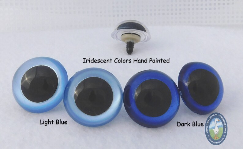 May include: Four plastic eyes for crafts, with black pupils and iridescent blue, light blue, and dark blue colors. The text "Iridescent Colors Hand Painted" is above the eyes. The text "Light Blue" is below the light blue eye. The text "Dark Blue" is below the dark blue eye.
