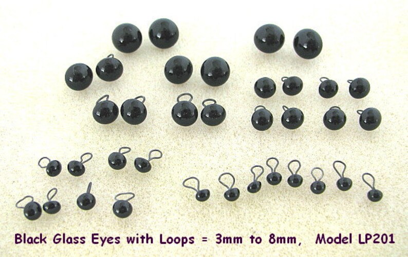 K&ouml;nnte beinhalten: Eine Sammlung schwarzer Glasaugen mit Schlaufen, in Gr&ouml;&szlig;en von 3 mm bis 8 mm. Die gl&auml;nzenden, kugelf&ouml;rmigen Augen sind in verschiedenen Gr&ouml;&szlig;en angeordnet, mit kleinen Drahtschlaufen. Der Text unten lautet "Black Glass Eyes with Loops = 3mm to 8mm, Model LP201."