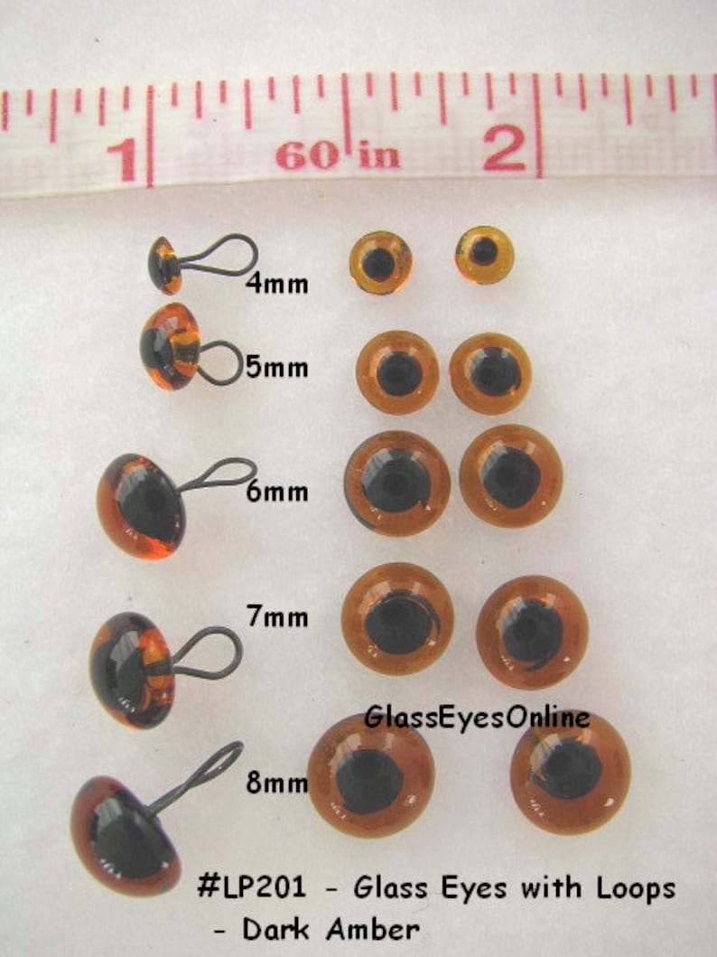 May include: Assortment of dark amber glass eyes with loops for crafts. The eyes range in size from 4mm to 8mm.  #LP201 - Glass Eyes with Loops - Dark Amber