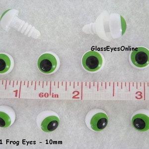 May include: A set of ten 10mm green plastic frog eyes with black pupils. The eyes are on a white surface with a ruler for scale. The text #FGE-1 Frog Eyes - 10mm is visible at the bottom of the image.