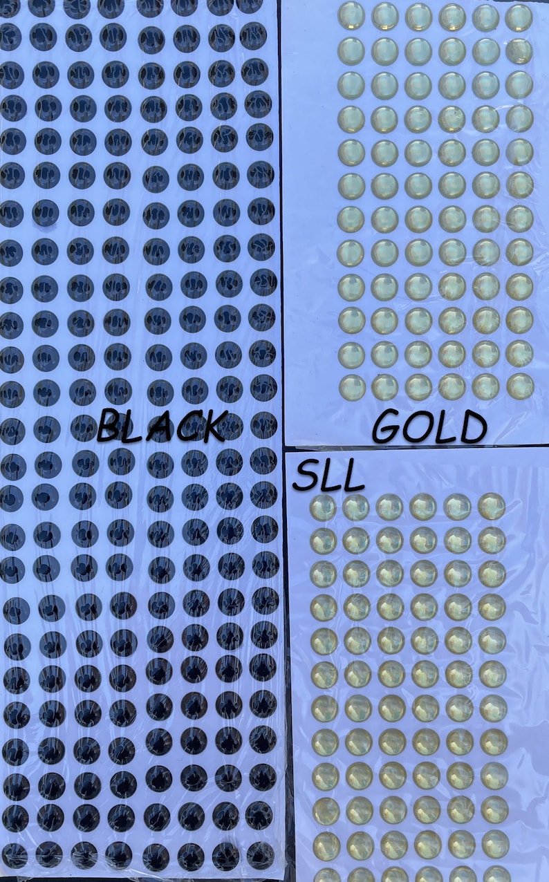 May include: A sheet of black and gold self-adhesive googly eyes. The sheet is divided into three sections, labeled "BLACK", "GOLD", and "SLL".