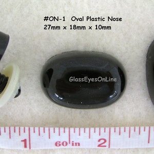 May include: Three black oval plastic noses, one with a white plastic screw-on back. The noses measure 27mm x 18mm x 10mm. The text #ON-1 Oval Plastic Nose 27mm x 18mm x 10mm and GlassEyesOnLine is visible in the image.